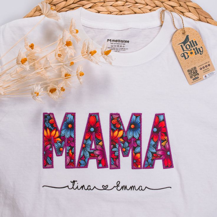 a white t - shirt with the word mama printed on it next to some flowers