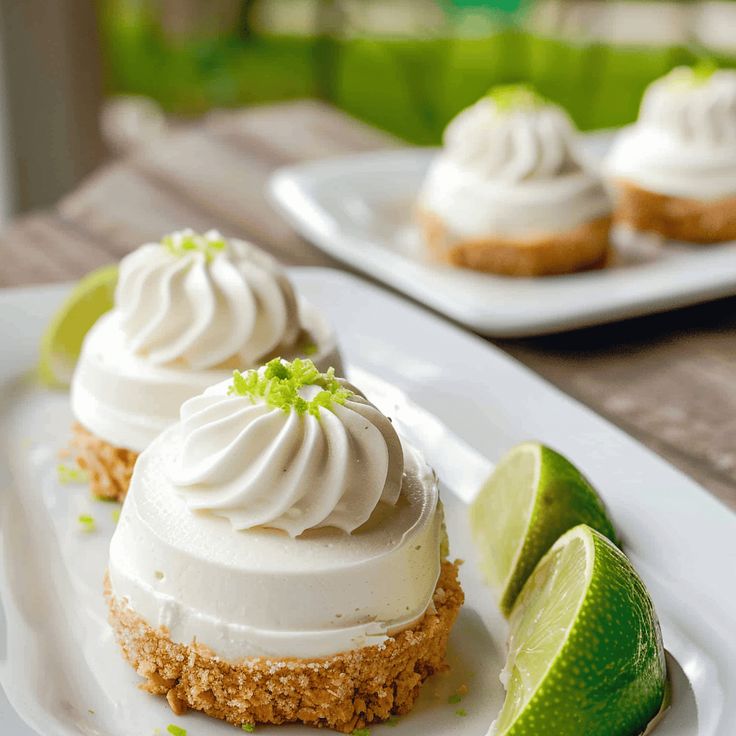 three small desserts on plates with lime wedges next to them and one is topped with whipped cream