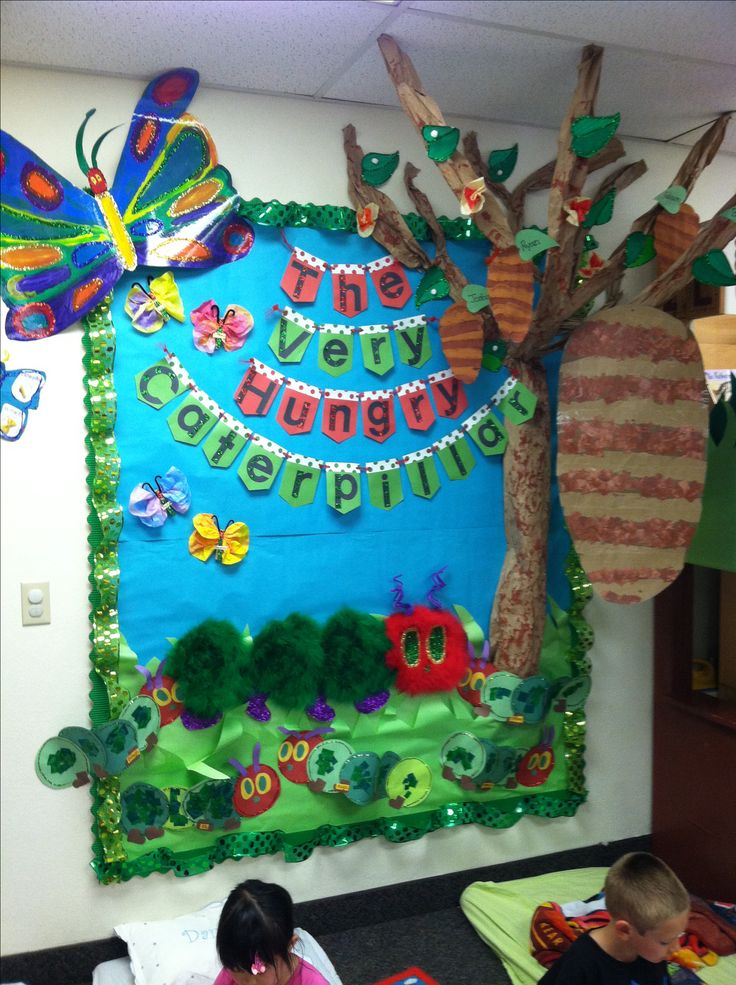 two children sitting on the floor in front of a bulletin board