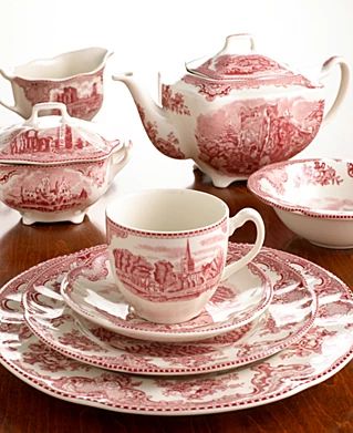 a red and white tea set on top of a wooden table next to other dishes