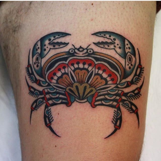 a crab tattoo on the thigh with an intricate design in red and blue colors is shown