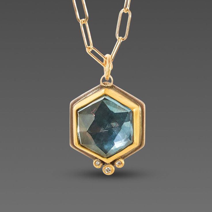 This striking necklace features a brilliant rose cut hexagonal London blue topaz wrapped in warm 22k gold and accented with a sparkling diamond trio. This lovely pendant is suspended on an 18k gold "paperclip" chain that adds texture and visual interest. The pendant measures approximately 5/8 inch tall. Backed in sterling silver. Matte finish. Emerald Cross, Necklace With Diamond, Topaz Necklace, Sparkling Diamond, Classic Jewelry, London Blue Topaz, London Blue, Sparkle Diamonds, 22k Gold