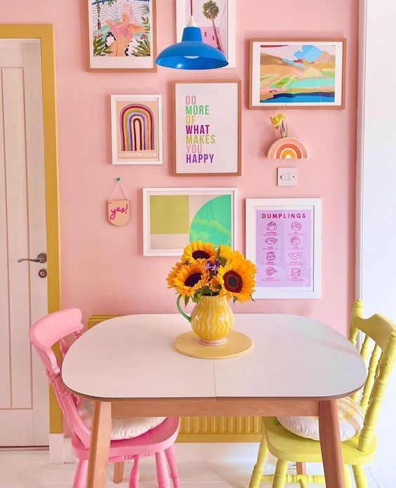 a dining room with pink walls and pictures on the wall