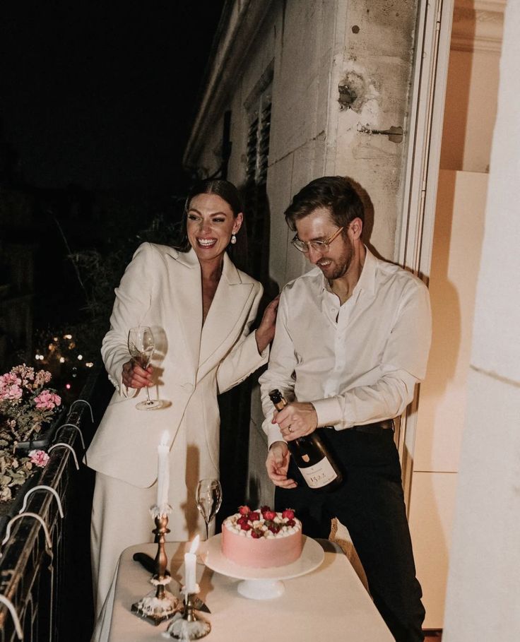 a man and woman standing next to a table with a cake on it