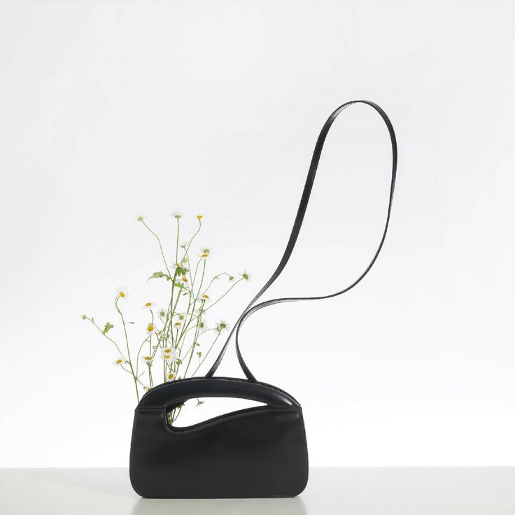 The Iconic Small Signature Curve Handbag has a unique curve shaped integral handle. A stylish and elegant magnetic roll top closure that can be worn over your shoulder, as a cross-body bag, or as a hand held handbag. Expertly hand crafted from the very finest deep black Italian calf leather. Comes with a internal card holder slip pocket.Detachable leather strap with a 56cm drop.Designed in London, Made in Florence, Italy. Fully lined. Natalie Dennis gold foil brand patch, Made in Italy gold foil Modern Baguette Bag With Adjustable Handle, Modern Shoulder Bag With Detachable Strap And Round Handle, Modern Top Handle Baguette Bag For On-the-go, Modern Evening Shoulder Bag With Adjustable Handle, Modern Crossbody Baguette Bag With Adjustable Handle, Modern Baguette Bag With Round Handle For Daily Use, Modern Baguette Bag With Detachable Top Handle, Modern Baguette Bag With Adjustable Double Handle, Modern Handheld Baguette Bag With Detachable Handle