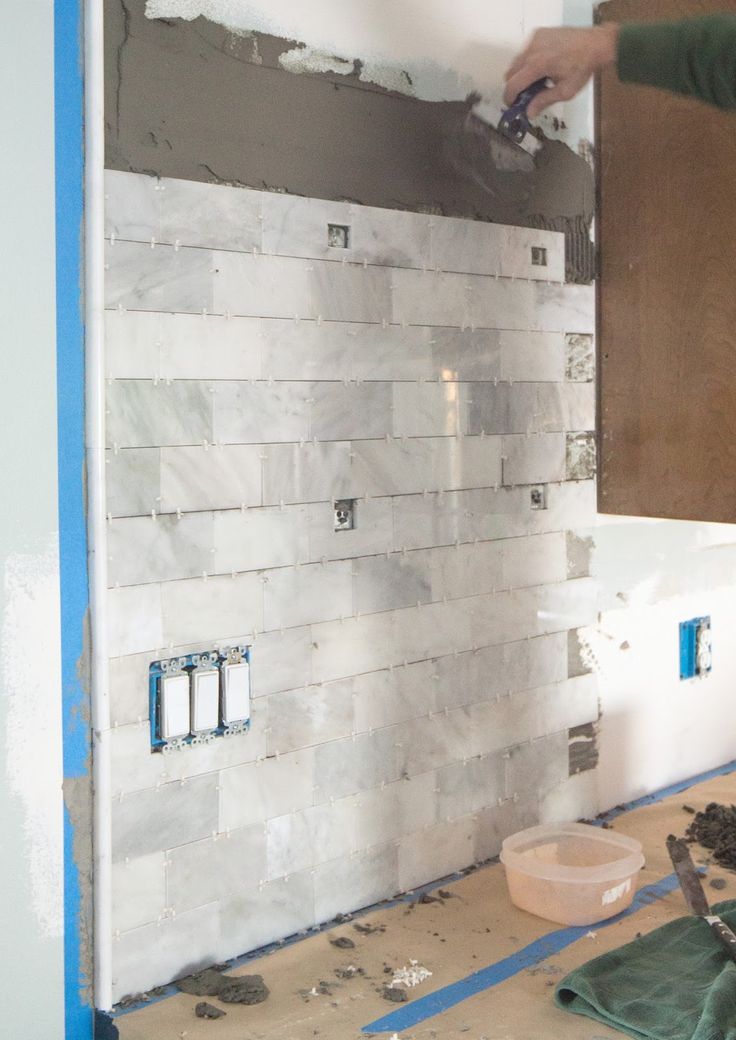 a man that is standing in front of a wall with some tiles on it and the walls are being remodeled