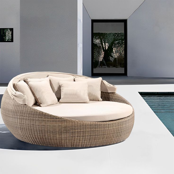 a couch sitting next to a swimming pool with pillows on the seat and pillowed back