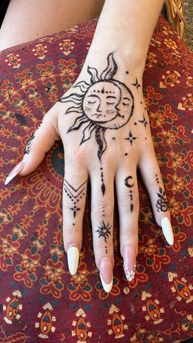 a woman's hand with sun and moon tattoos on it