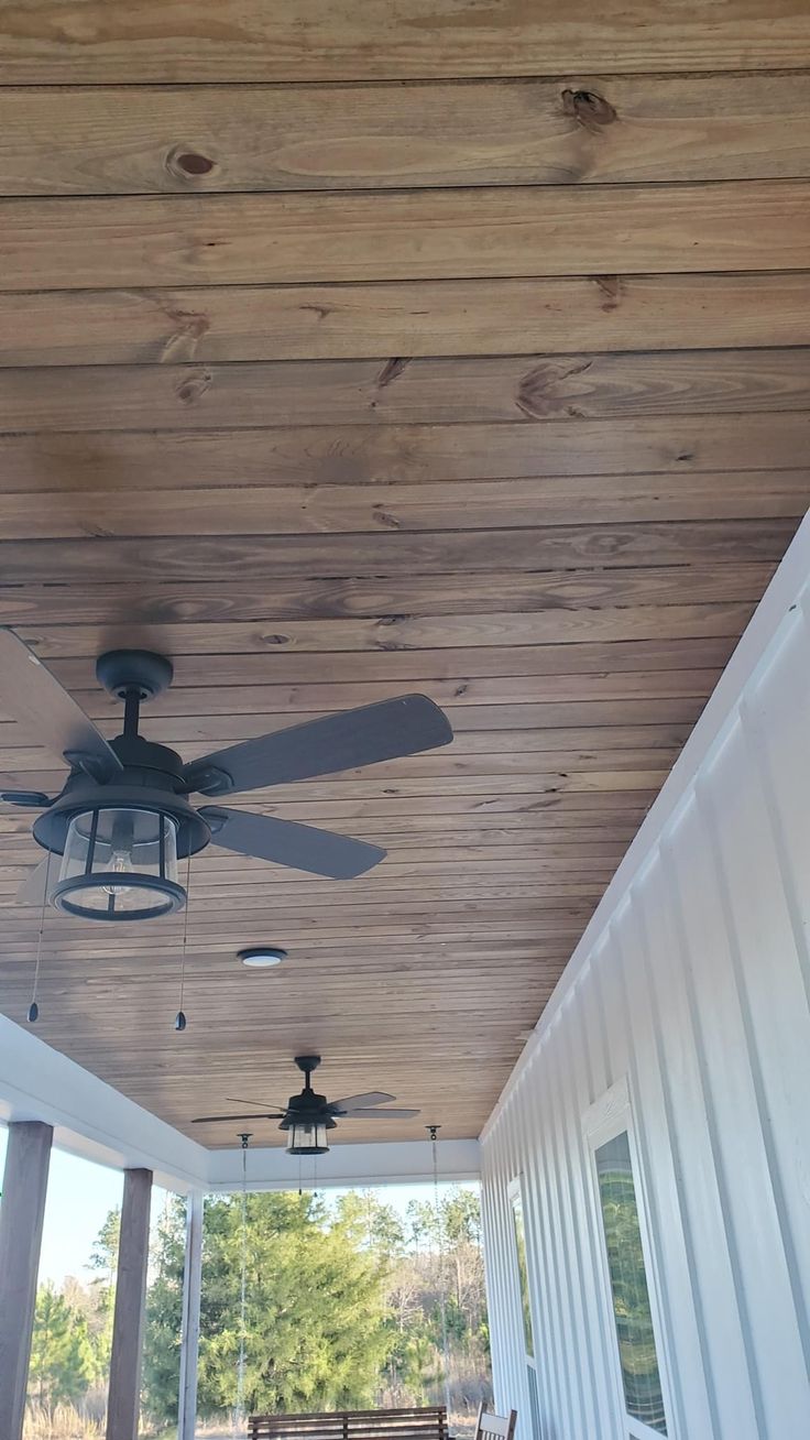 a ceiling fan on the outside of a house with wood paneling and white siding