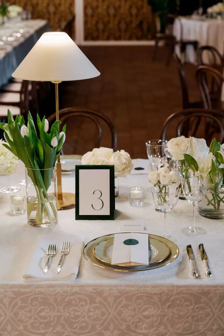 the table is set with white flowers and place settings