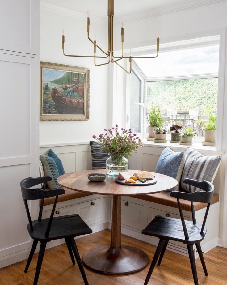 a dining room table with two chairs and a bowl of fruit on it