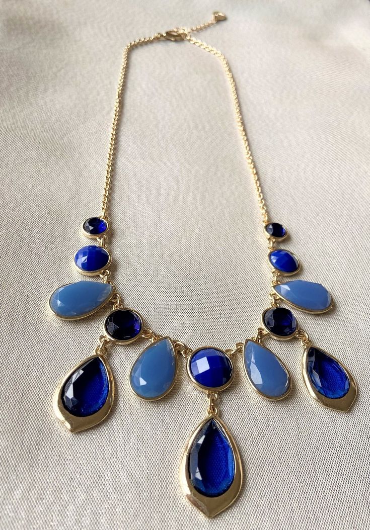 "This stunning gold, dark blue and light blue jeweled statement necklace is adorned with several teardrop and circular blue jewels accented by a beautiful gold chain. Necklace has a 3\" built in extender, lobster claw clasp, and finishing bead. This would make a gorgeous gift or can compliment any outfit easily. Approximate length, about: 20\" / Statement Necklace 》 P A C K A G I N G 《 Your jewelry will be nicely packaged. If one or more items are gifts, please leave a note at checkout and we'll Blue Teardrop Pendant Jewelry With Adjustable Chain, Blue Dangle Jewelry With Adjustable Chain, Blue Teardrop Pendant Jewelry For Party, Blue Teardrop Pendant Necklace With Adjustable Chain, Blue Teardrop Necklace With Adjustable Chain, Blue Teardrop Drop Necklace For Party, Blue Dangle Necklaces For Party, Blue Teardrop Necklace For Party, Blue Drop Necklace For Party