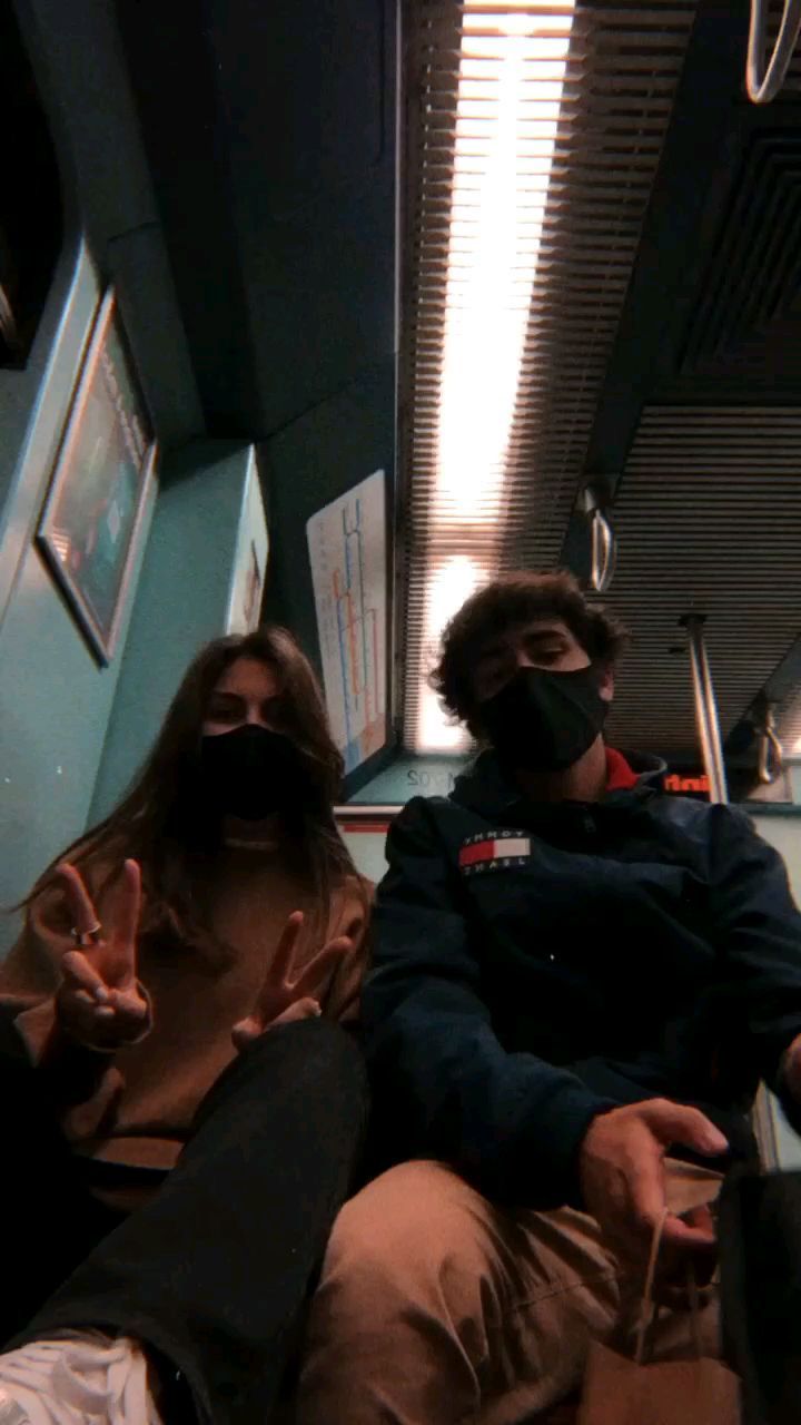 two people sitting on a train with masks on