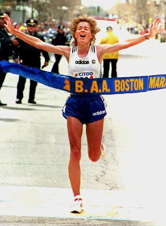 a woman crosses the finish line in a marathon