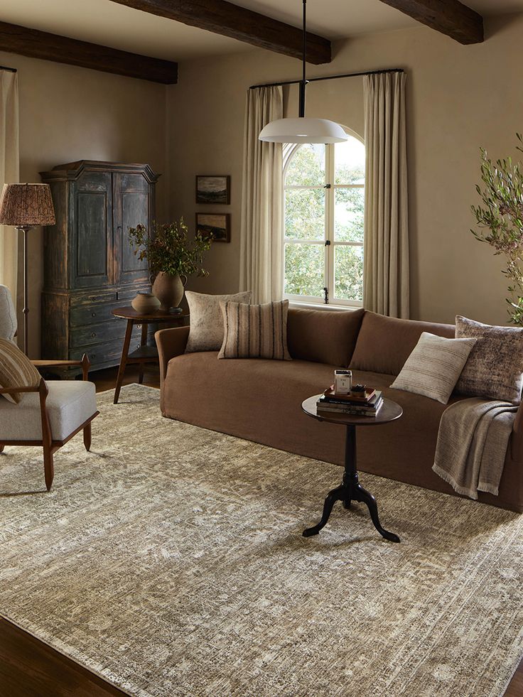 a living room filled with furniture and a large rug on top of a wooden floor