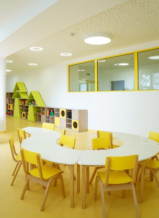 an empty room with yellow chairs and tables in it, next to bookshelves