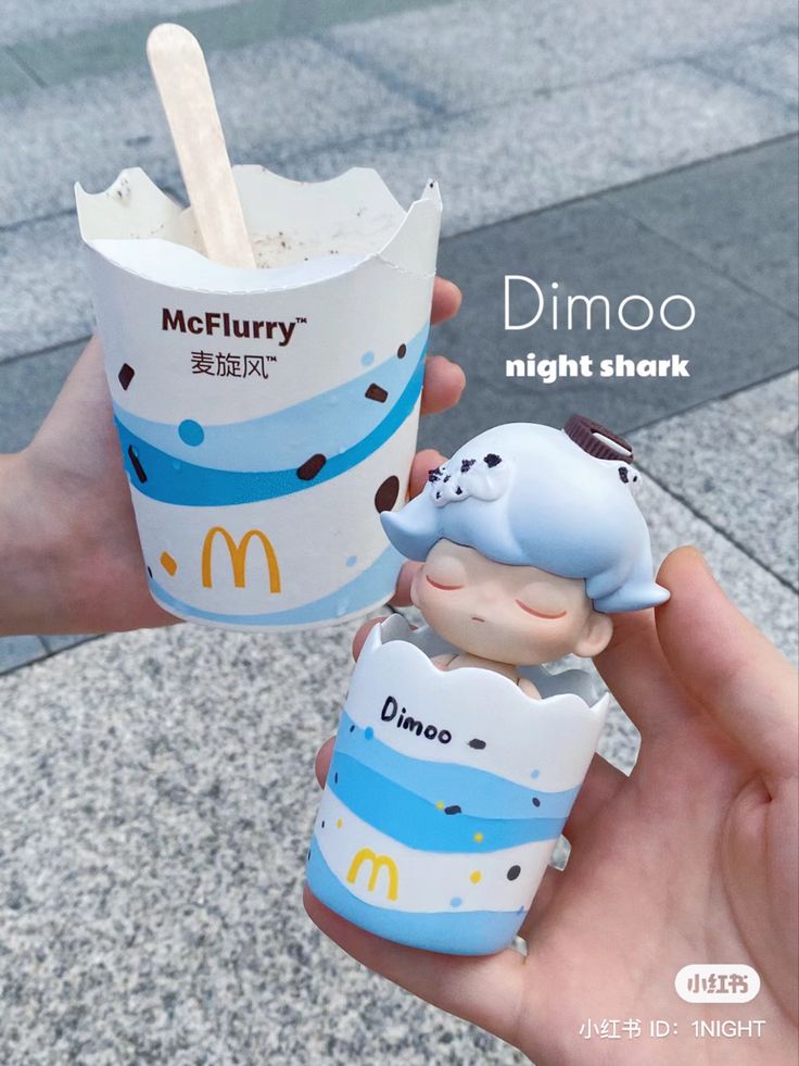 someone is holding up a mcdonald's ice cream cup and an elephant figurine