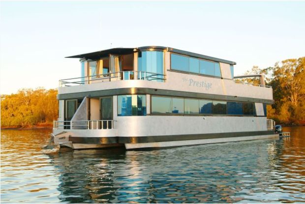 a houseboat floating on top of a lake surrounded by trees in the fall season