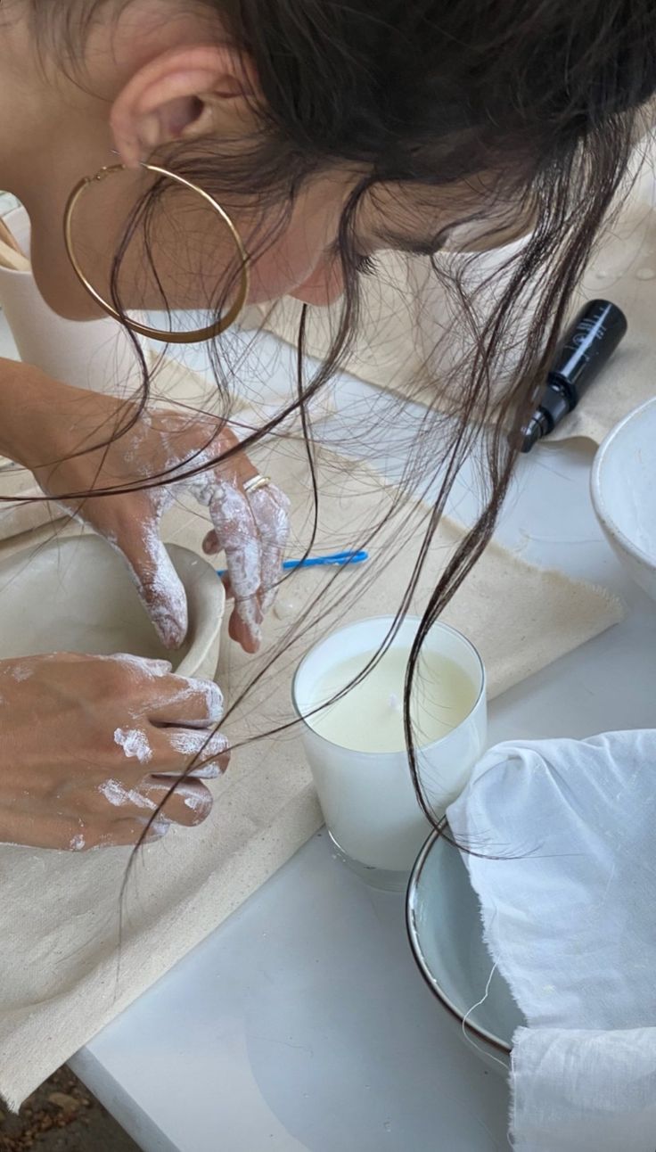 a woman is washing her hands in a bowl with some white stuff on the counter