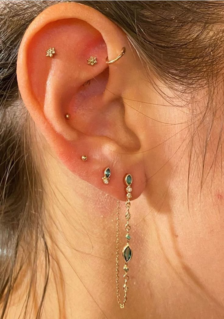 a woman's ear with some piercings attached to the back of her ear