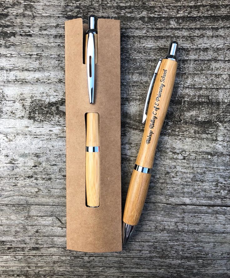 a wooden pen sitting inside of a cardboard box next to a metal ballpoint pen