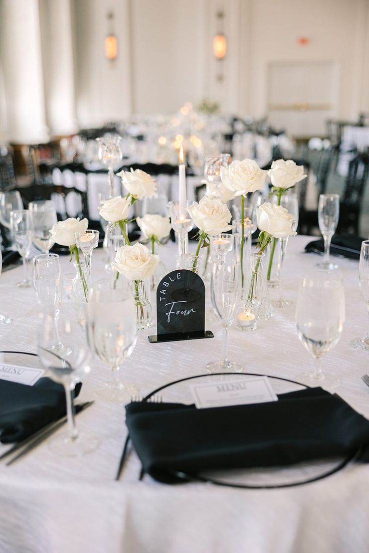 the table is set with white flowers and black napkins for an elegant wedding reception