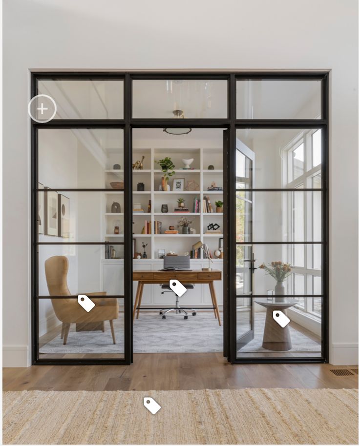 an office with glass walls and wooden flooring is seen through the doors to another room