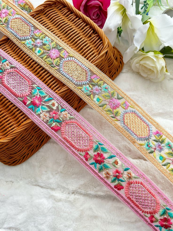 two different colored ribbons sitting next to each other on a white surface with flowers in the background