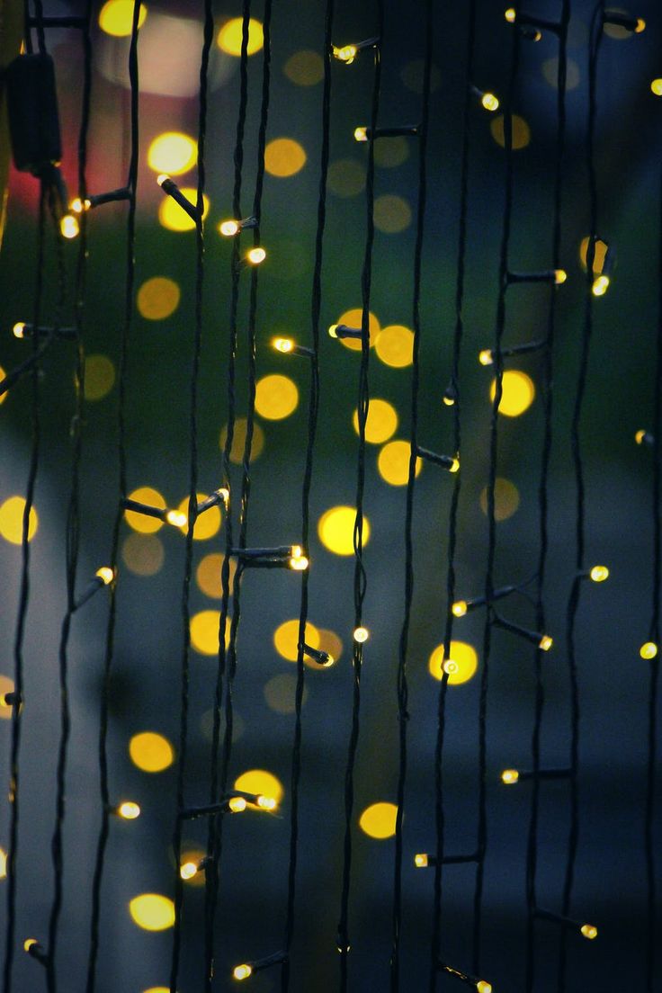 some lights that are hanging from the side of a building in the night time with blurry lights behind them