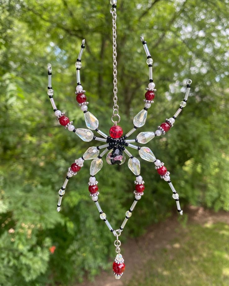 a glass sun catcher hanging from a chain in front of a tree filled with leaves