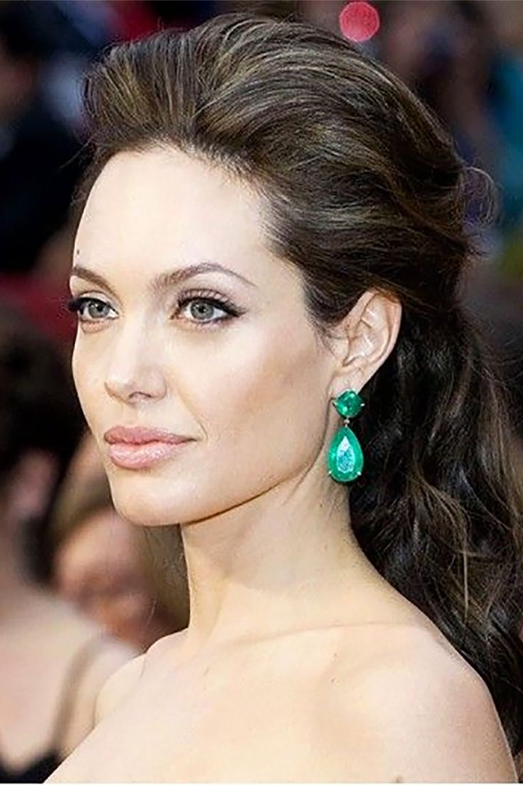 a woman with long hair wearing green earrings