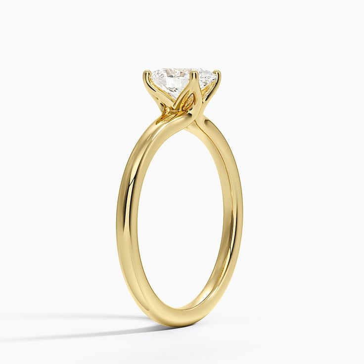 a yellow gold engagement ring with a princess cut diamond in the center, on a white background