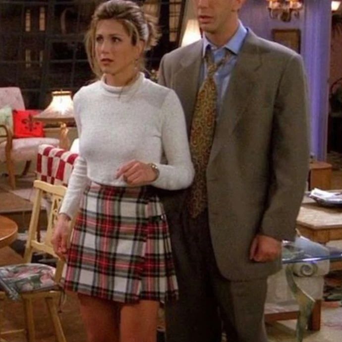 the young man and woman are standing in front of each other, wearing plaid skirts