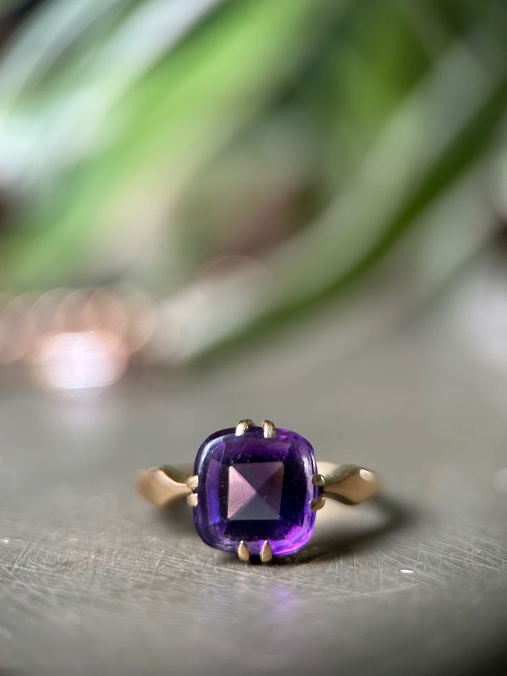 "This antique amethyst ring is utterly divine, with a rich solid 18ct gold band that really ignites that lavender-hued gemstone.  The amethyst is an unusual 'buff-top' cut, with a faceted bottom and smooth cabochon top, in the shape of a classic cushion cut. It is held securely in place by 4 double prongs on an 18ct gold setting.  The band is simple at the back, with just a touch of detail near the shoulders which taper to a point leading to that gorgeous stone. If you are intrigued by the world of spiritual healing, amethyst is thought to help ease sadness and alleviate stress. Sounds good to me!  Hallmarks: \"18CT\" tested as 18ct gold.  Condition: Very good condition. This ring still looks fab for an antique piece, the gold has turned buttery soft and still lovely and bright. There is a Timeless Amethyst Ring As A Gift, Timeless Amethyst Promise Ring, Elegant Lavender Amethyst Ring In 14k Gold, Timeless Amethyst Gemstone Rings, Timeless Purple Rings For Gifts, Timeless Purple Rings As Gifts, Timeless Purple Rings Perfect For Gifts, Heirloom Style Amethyst Ring With Polished Finish, Purple Amethyst Ring For Anniversary