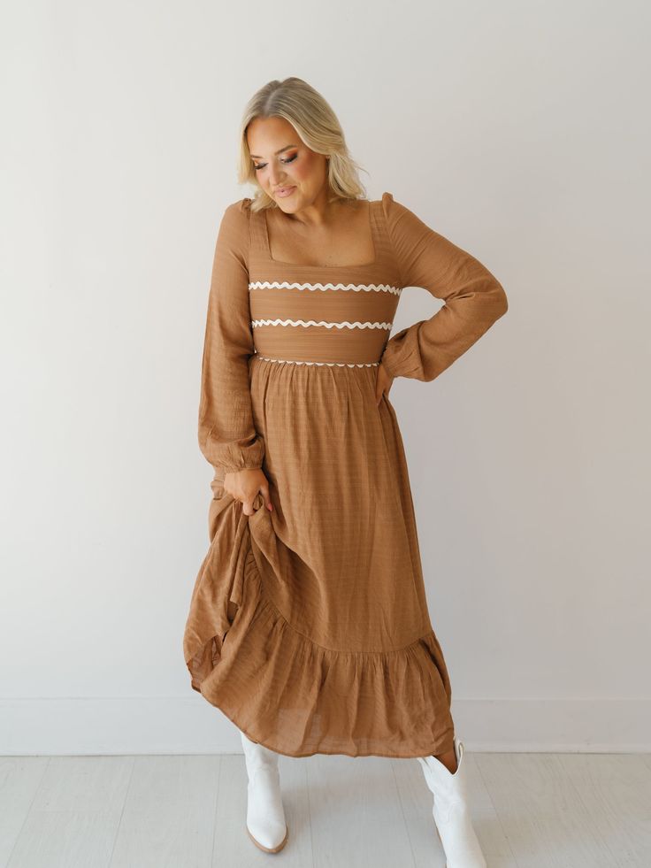 Twirl around in the "Wynn Dress!" This elevated maxi dress is perfect for church or work because of its modest design and fall color! It boasts a soft waffle print fabric, mocha base with ivory rick-rack along the bust, and long balloon sleeves. Easy to pair with boots or heels to complete the look! Detailed Fit: Square neckline maxi dress Cinching at top of shoulder Tie at back of neckline Zipper in the back Waffle pattern throughout skirt Double-lined Overfall Fit: Fitted through bust with a r Brown Ruffled Maxi Dress, Fall Maxi Dress With Lace Trim, Modest Flowy Maxi Dress For Fall, Flowy Modest Maxi Dress For Fall, Maxi Dress With Lace Trim For Fall, Lace Trim Maxi Dress For Fall, Modest Midi Dress With Lace Trim, Cream Ruffled Maxi Dress For Fall, Modest Ruffled Maxi Dress For Fall