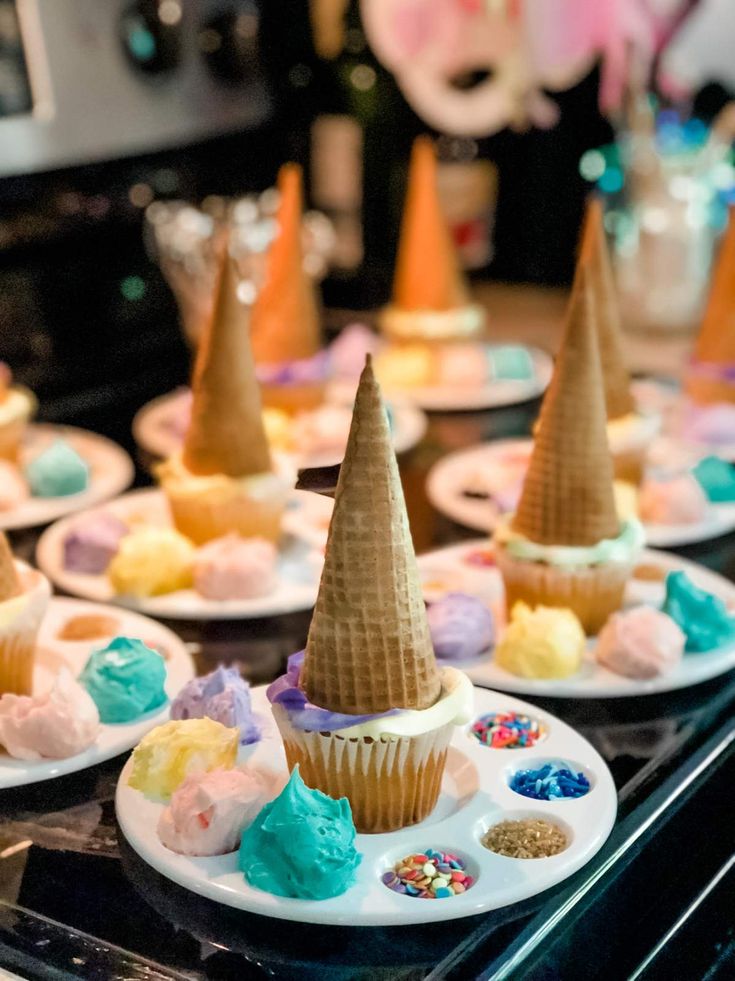 cupcakes with ice cream cones and sprinkles are on plates in the kitchen