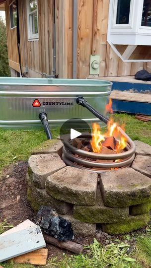 a fire pit sitting on top of a grass covered field next to a metal container