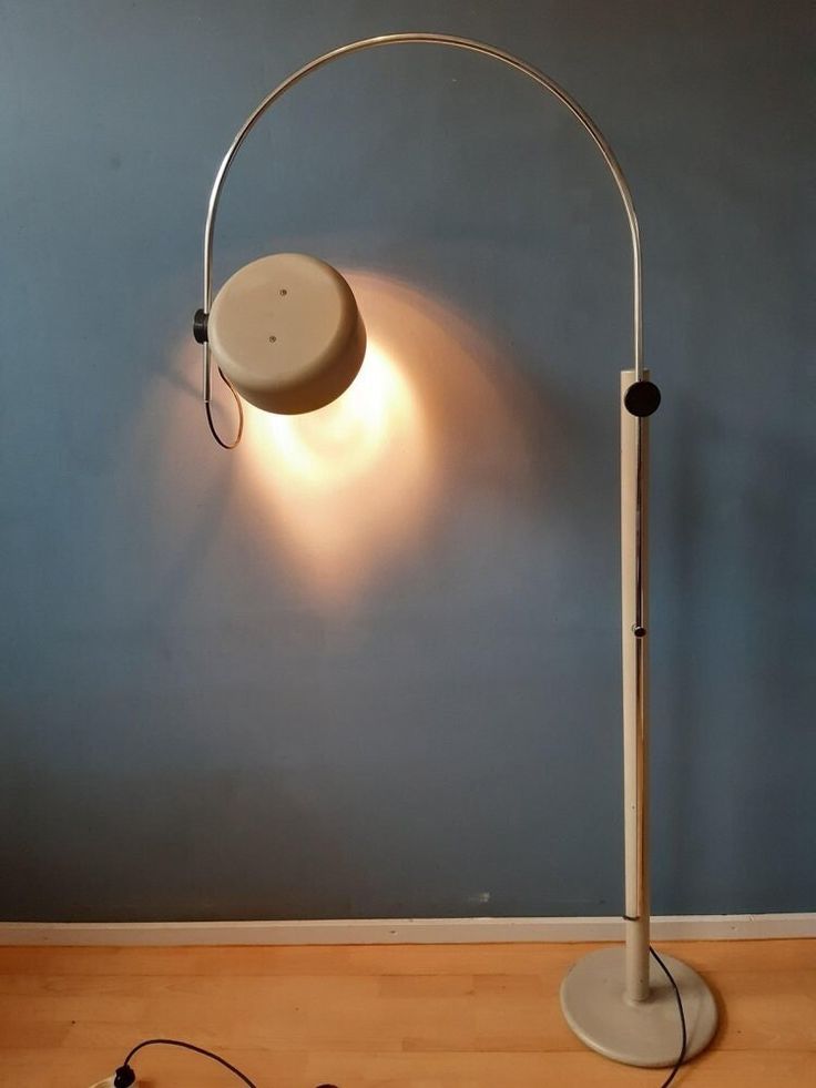 a lamp that is on top of a wooden floor next to a blue wall and some wires