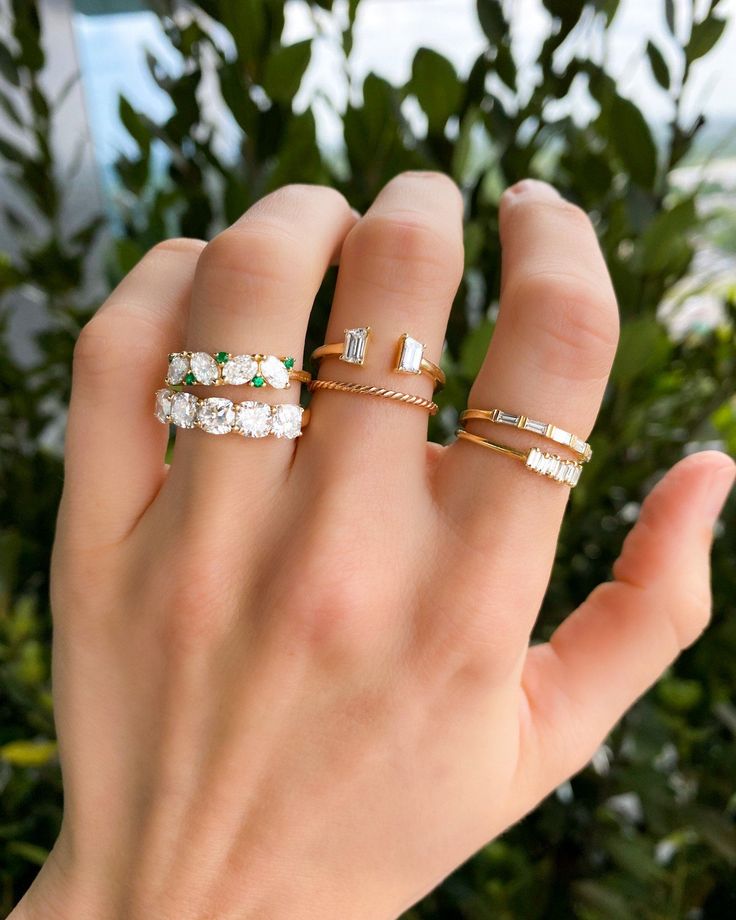 a woman's hand with three different rings on her fingers and one is holding the other