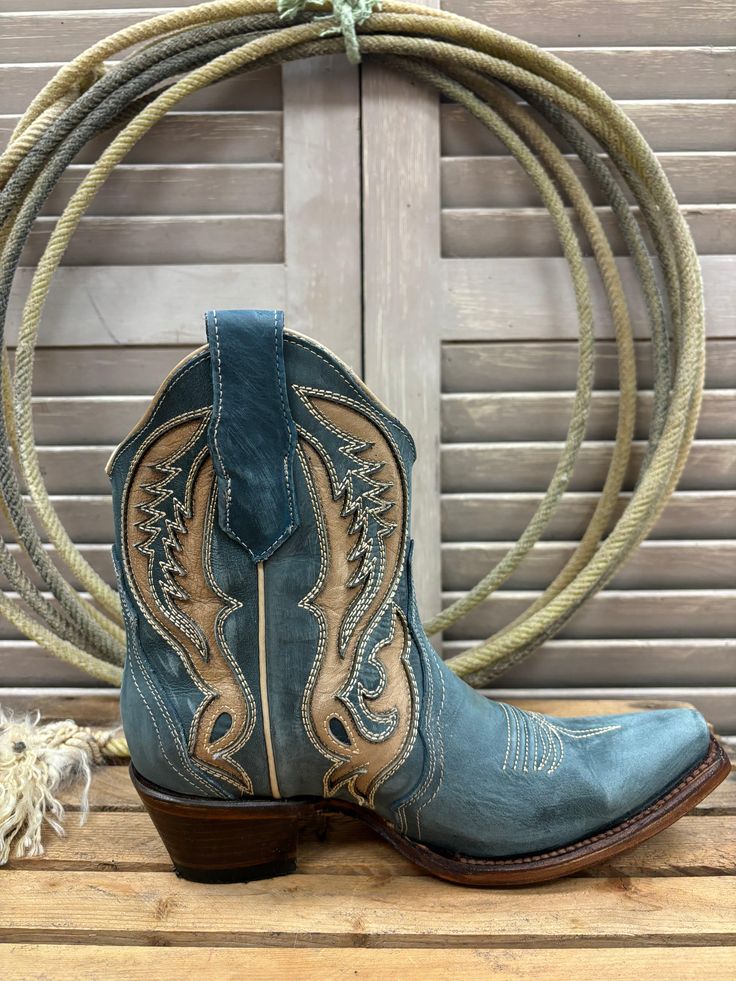 Looking for a stylish and comfortable boot? Look no further than the Corral Circle G Women's Distressed Blue & Tan Inlay Ankle Boot. Made from genuine leather, this boot stands out with its intricate details. With its quality and craftsmanship, Circle G Boots are sure to become a favorite brand for those who love cowgirl boots. Handcrafted by more than 90 artisans. Authentic Cowgirl Style Snip Toe Pull Tabs 7" Shaft Height 1.5" Cowboy Heel Cowhide Outsole Pig Lining Goodyear Welt Color: Distress Womens Ball Caps, Cowgirl Ankle Boots, Toddler Boy Tops, Boot Stand, Wedding Boots, Youth Shoes, Toddler Boots, Harness Boots, Mens Cowboy Boots