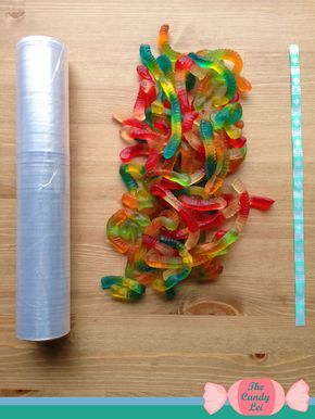 some gummy bears and a roll of tape on top of a wooden table next to a spool of thread