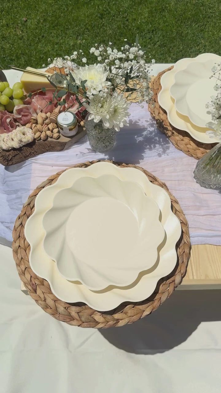 plates and bowls on a picnic table with flowers