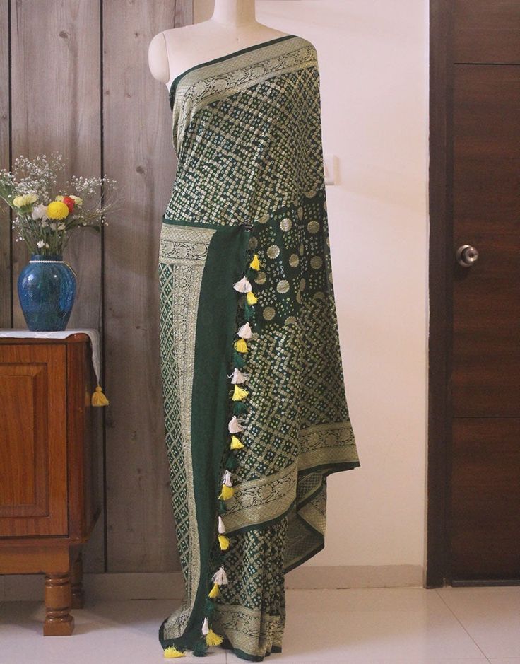 A spectacular Handwoven Deep Green Pure Banarasi Handloom Khaddi Georgette Bandhani Saree in gorgeous pattern. Its a fusion of karigari of Banarasi and Gujarati. Additional Information Color : Green Technique: Bandhani is a tye & dye technique in which fabric is pinched with nails and tied with thread and then dyed to create fabulous patterns. Fabric: Pure Georgette Blouse Piece: Included Since this product is handwoven, there might be slight irregularities. But doesn't that add to the singu Festival Brocade Pre-draped Saree With Cutdana, Brocade Pre-draped Saree With Traditional Patterns, Unstitched Bohemian Pre-draped Saree With Dupatta, Bohemian Art Silk Pre-draped Saree With Dupatta, Bohemian Pre-draped Saree For Transitional Season, Bohemian Traditional Wear With Bandhani Print For Festivals, Bohemian Pre-draped Saree With Motifs For Navratri, Bohemian Bandhani Traditional Wear For Festivals, Bohemian Banarasi Silk Saree