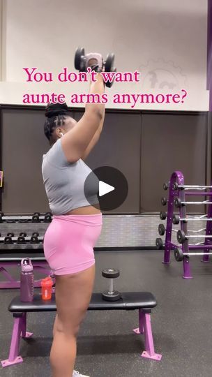 a woman in pink shorts doing squats on a bench with dumbbells behind her