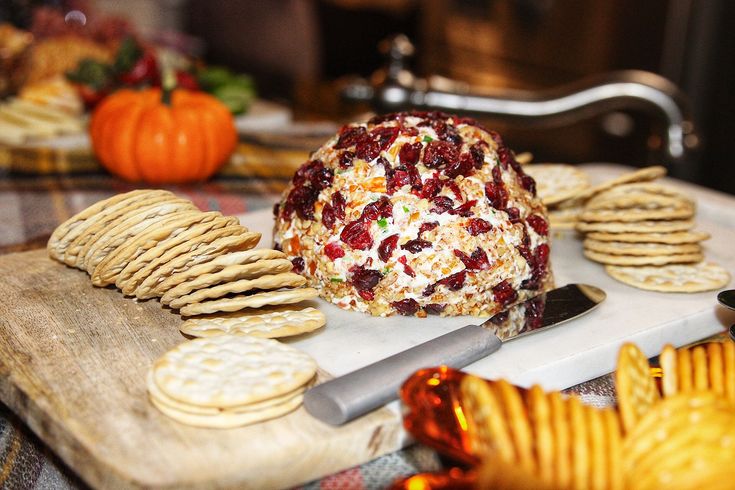 crackers, crackers and cheese are arranged on a cutting board with pumpkins in the background