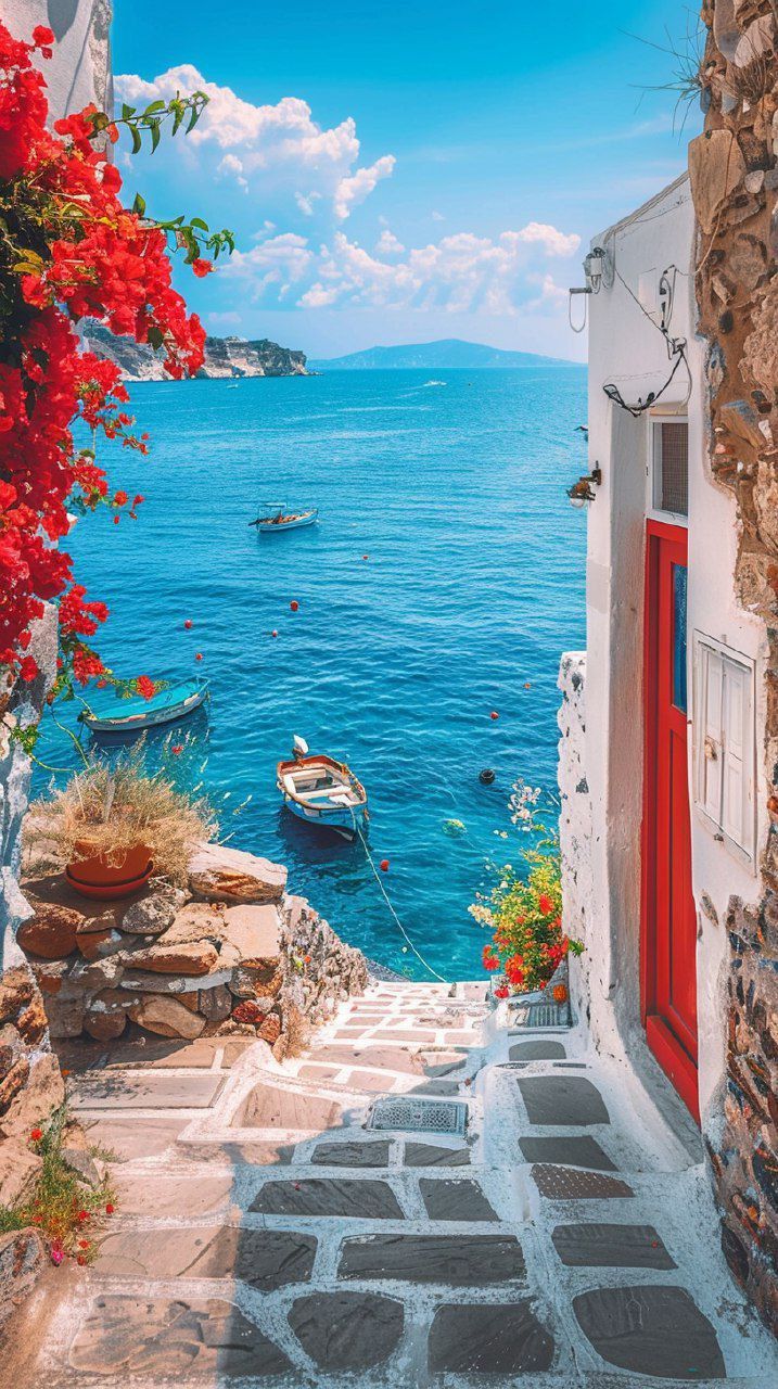 an alley leading to the water with boats in it and red flowers growing on the steps