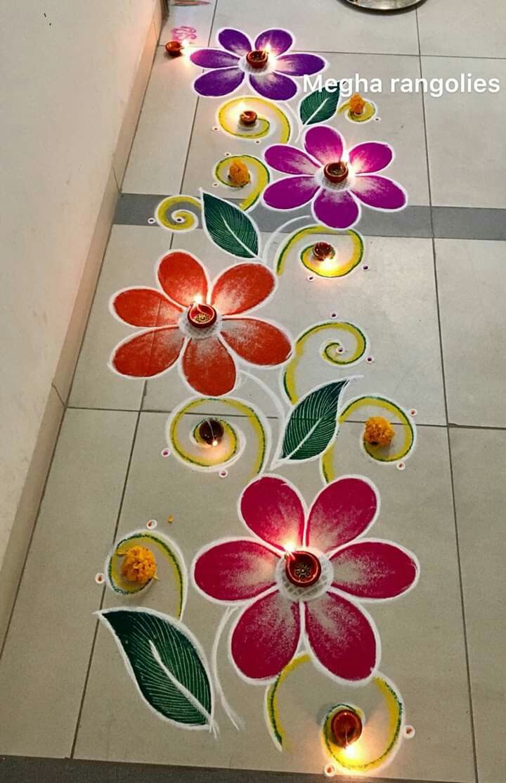 colorful flower design on the floor with candles in front of it for diwaling