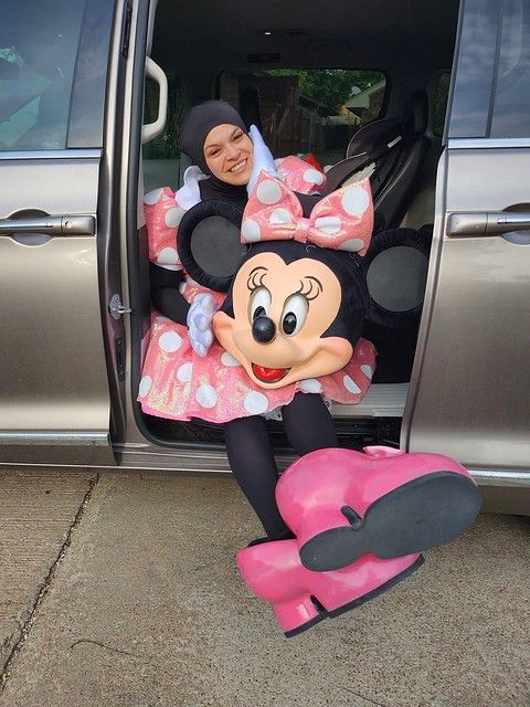 a woman sitting in the back of a car next to a minnie mouse