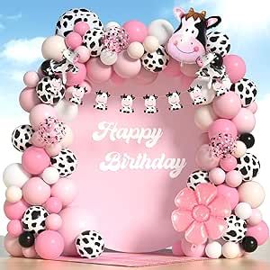 a pink and black cow birthday arch with balloons