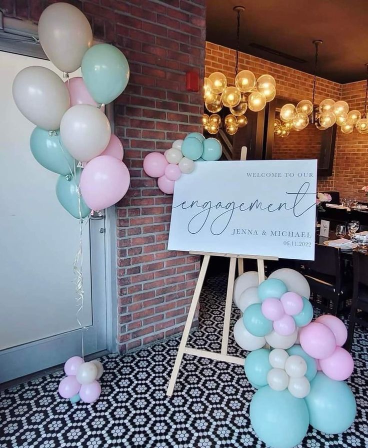 a sign that says engagement and balloons are in front of a brick wall with chandeliers